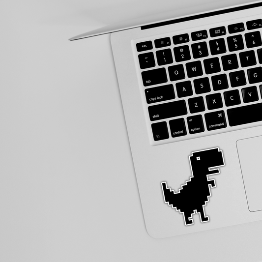 Laptop with pixel dinosaur sticker near keyboard, Sticksnap tech accessory