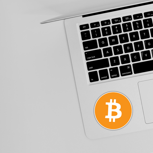 Laptop with Bitcoin logo sticker on silver surface, Sticksnap tech accessory